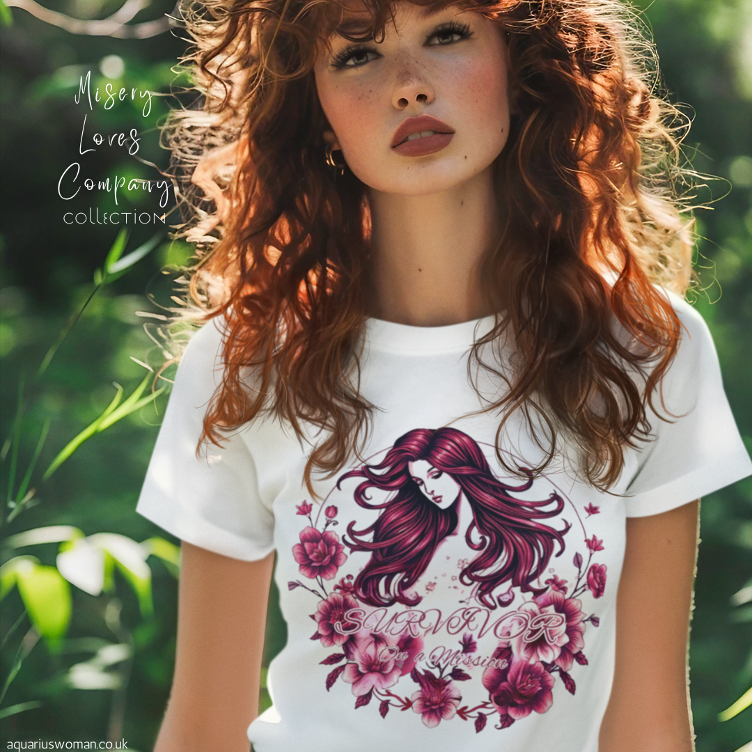 A woman wearing the 'Survivor on a Mission' t-shirt from the Misery Loves Company Collection by Aquarius Woman. The design showcases intricate floral details and a powerful feminine figure, representing resilience, transformation, and the journey of healing.