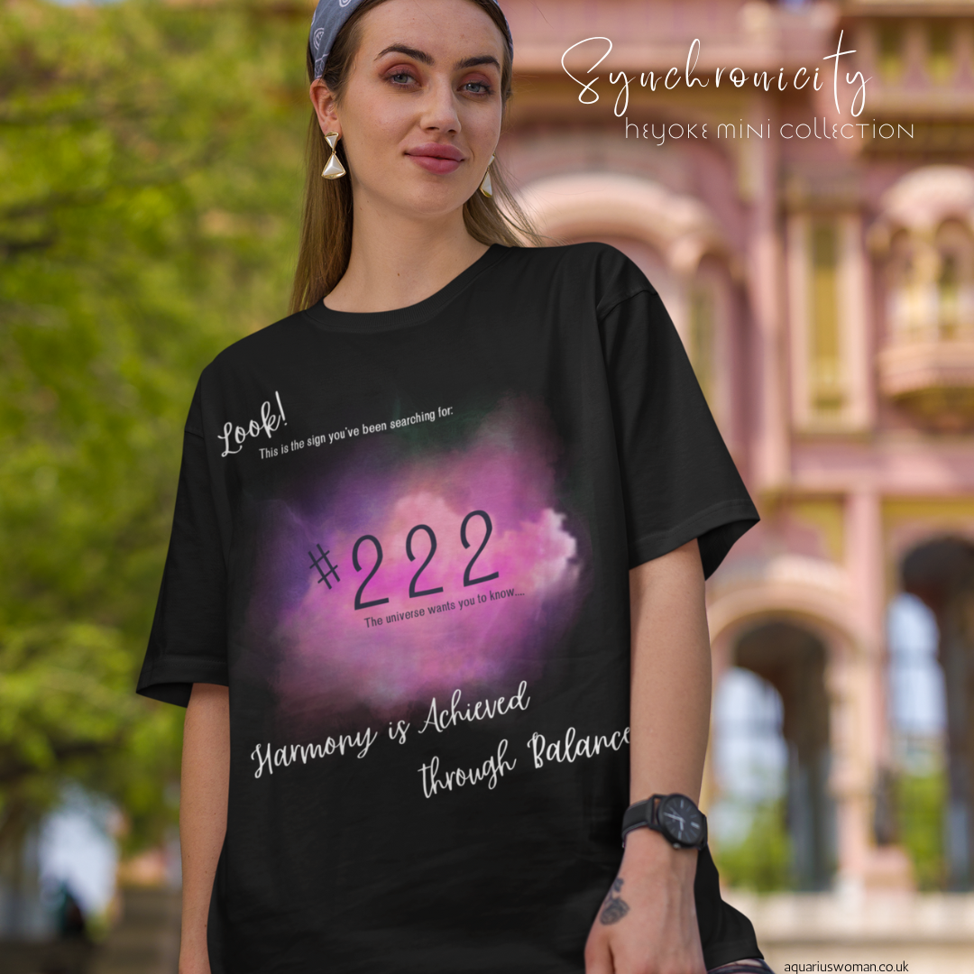 A woman wearing a black '222' angel number t-shirt from the Synchronicity Mini-Collection, part of the Heyoke Collection by Aquarius Woman. The design features a cosmic-inspired aura with the number 222, symbolising balance, alignment, and divine guidance.